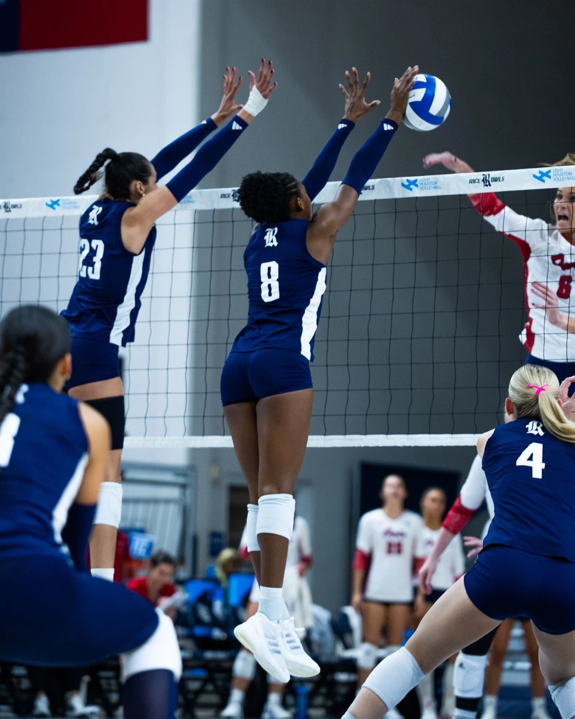 Rice University volleyball players blocking at the net during a match